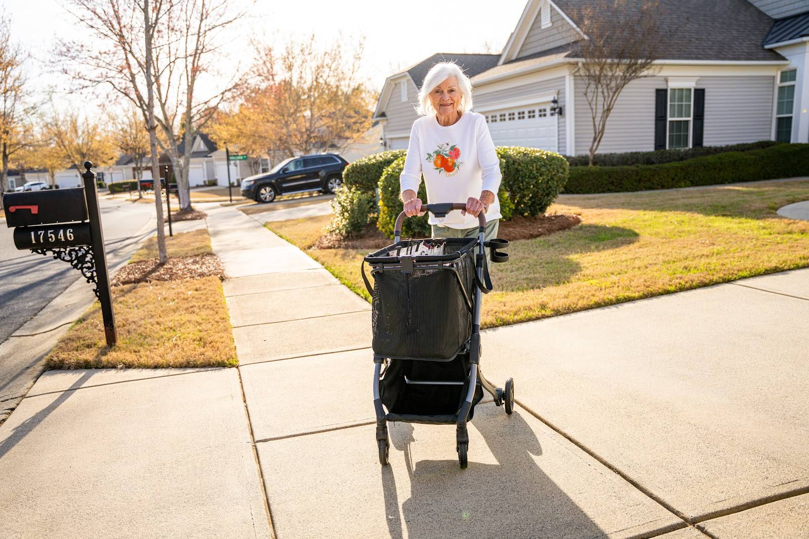 A woman walks her Strolee Stability Shopper along a neighborhood sidewalk on a sunny afternoon