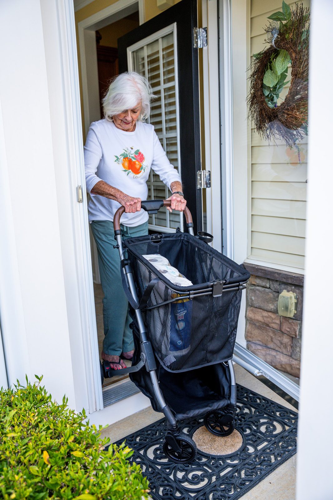 A woman steps out her front door with her Strolee Stability Shopper