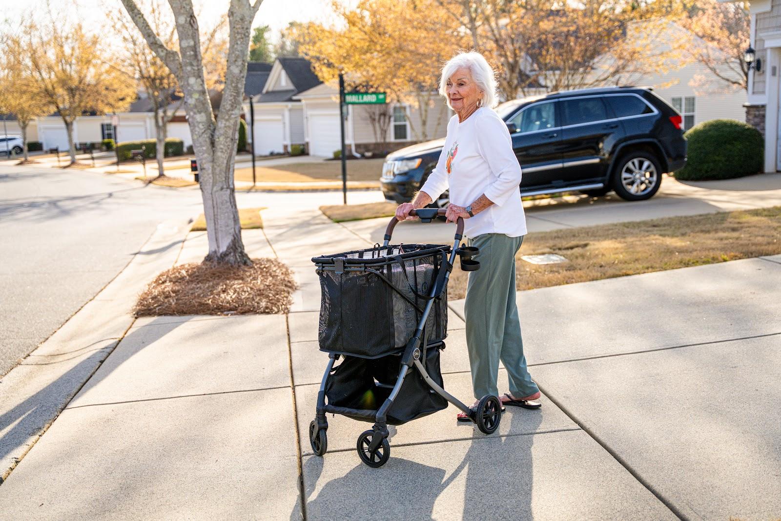 A woman stands with her Strolee Stability Shopper on her driveway beside her parked car